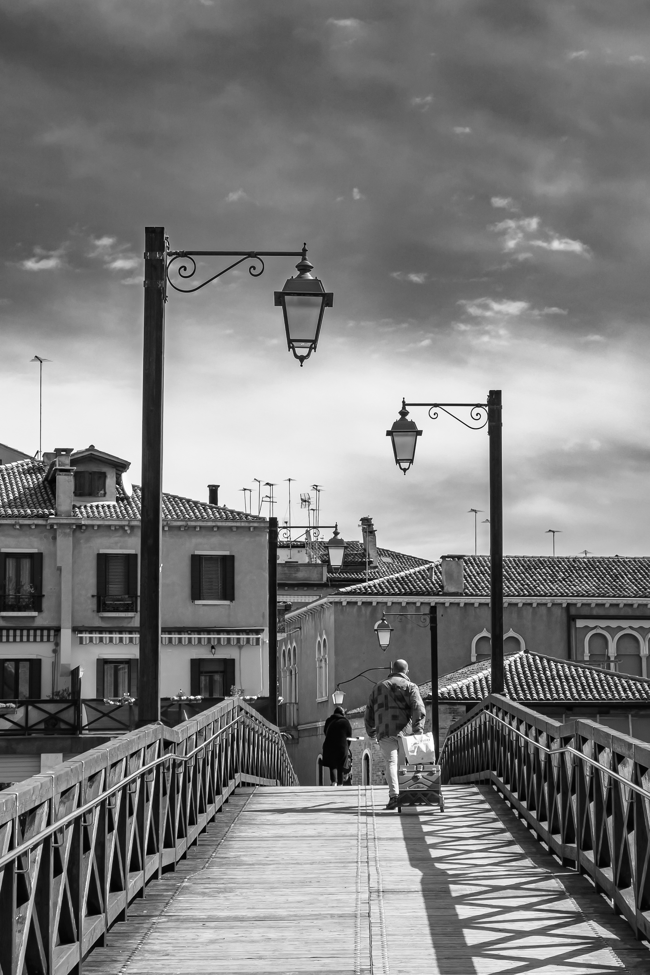 man walking over wooden bridge in Venice