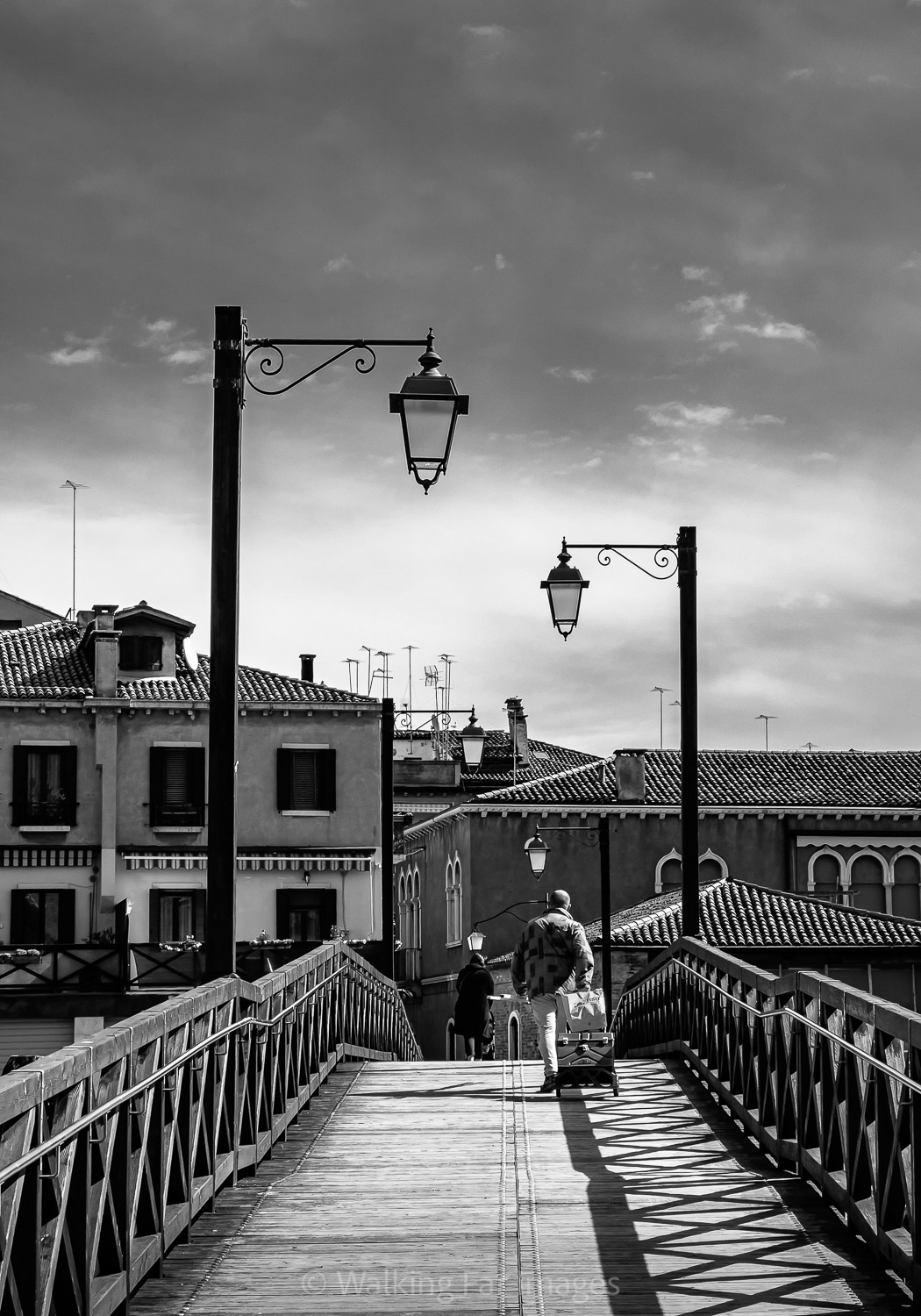 man walking over wooden bridge in Venice